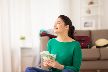 Image showing happy woman with money and travel bag at home