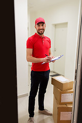 Image showing delivery man with boxes and clipboard at door