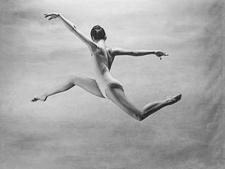 Image showing Young beautiful modern style dancer jumping on a studio background