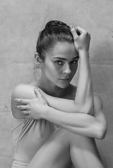 Image showing Tired ballet dancer sitting on the wooden floor on a pink background