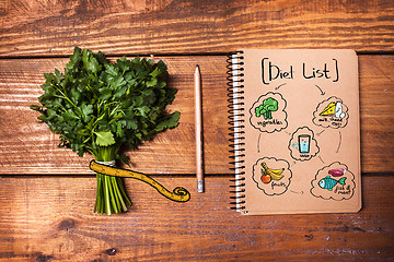 Image showing Blank notebook and pencil with a bunch of herbs on wooden table