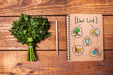 Image showing Blank notebook and pencil with a bunch of herbs on wooden table