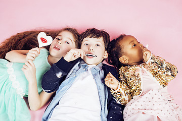 Image showing lifestyle people concept: diverse nation children playing together, caucasian boy with african little girl holding candy happy smiling 