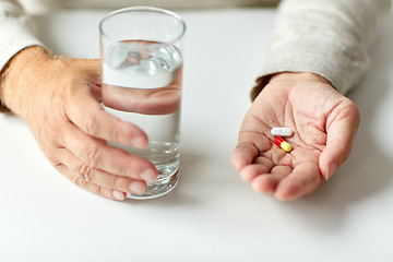 Image showing close up of hands with medicine pills and water