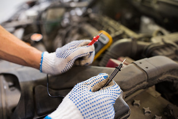 Image showing auto mechanic man with multimeter testing battery