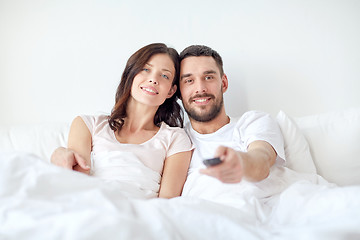 Image showing happy couple lying in bed at home and watching tv