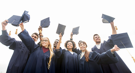 Image showing happy students or bachelors waving mortar boards