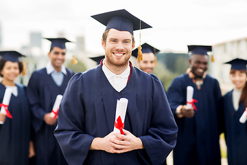 Image showing happy students in mortar boards with diplomas