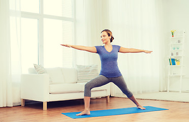 Image showing woman making yoga warrior pose on mat