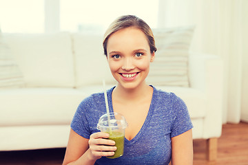 Image showing happy woman with smoothie sitting on mat at home