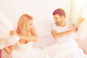 Image showing happy couple having pillow fight in bed at home