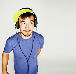 Image showing young asian man in hat and headphones listening music on white b