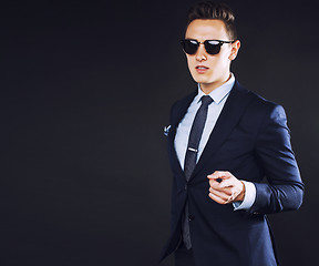 Image showing young pretty business man standing on black background, modern h