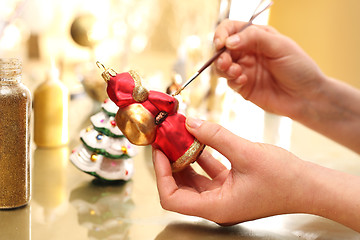 Image showing Decorating Christmas of glass balls. Woman paints with a brush Christmas balls 