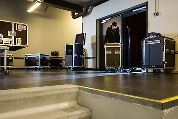 Image showing Roadie leaning on a flightcase next to the stage