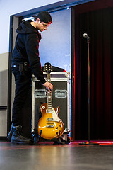 Image showing Roadie putting down the guitar for a band member