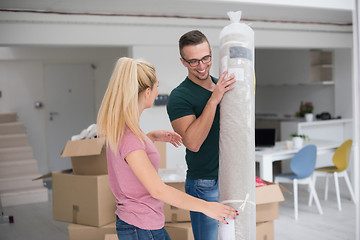 Image showing couple carrying a carpet moving in to new home