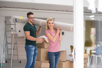 Image showing couple carrying a carpet moving in to new home