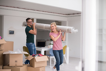 Image showing couple carrying a carpet moving in to new home