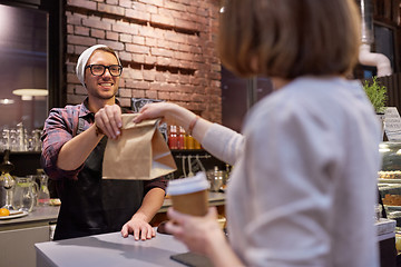 Image showing woman taking paper bag from seller at cafe