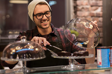 Image showing man or barman with cakes and tongs at cafe counter