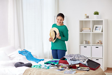 Image showing woman packing travel bag at home or hotel room