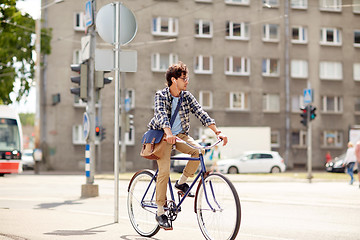 Image showing young hipster man with bag riding fixed gear bike