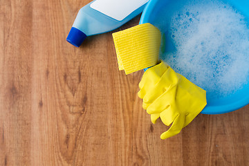 Image showing basin with cleaning stuff on wooden background