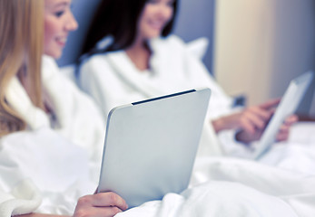 Image showing happy women in bathrobes with tablet pc at hotel