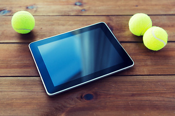 Image showing close up of tennis balls and tablet pc on wood