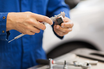 Image showing mechanic with calipers measures detail at workshop