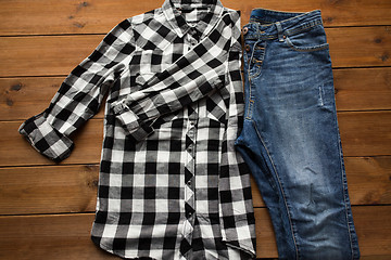 Image showing close up of checkered shirt and jeans on wood