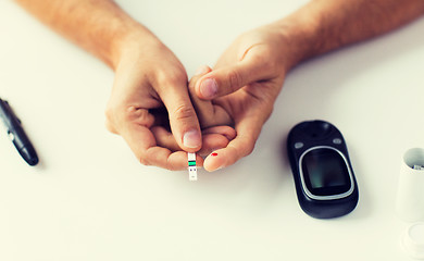 Image showing close up of man checking blood sugar by glucometer