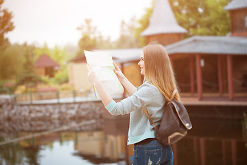 Image showing Traveler girl searching right direction on map, orange sunset light, traveling along Europe