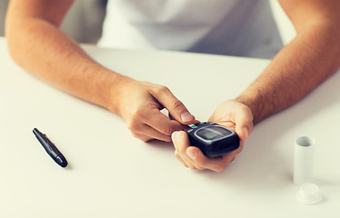 Image showing close up of man checking blood sugar by glucometer