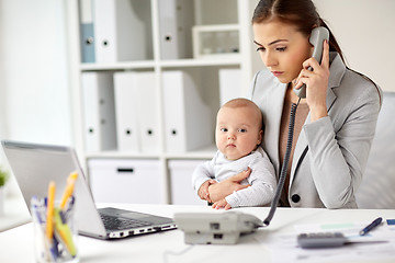 Image showing businesswoman with baby calling on phone at office