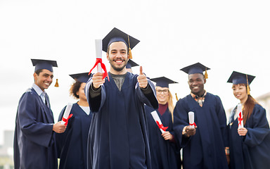 Image showing happy students with diplomas showing thumbs up