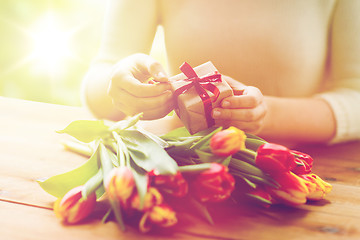 Image showing close up of woman with gift box and tulip flowers