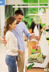 Image showing happy couple weighing cabbage on scale at grocery