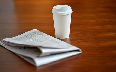 Image showing coffee drink in paper cup and newspaper on table