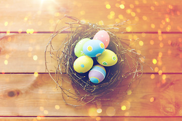 Image showing close up of colored easter eggs in nest on wood