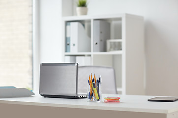 Image showing laptop with pen and stickers on office table