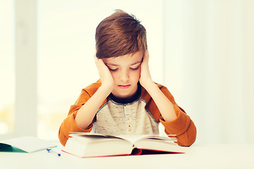 Image showing student boy reading book or textbook at home