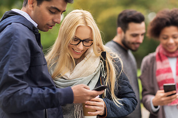 Image showing happy friends with smartphone and coffee outdoors