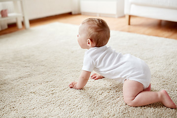 Image showing little baby in diaper crawling on floor at home