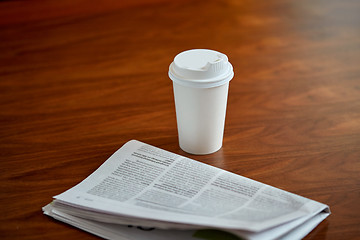 Image showing coffee drink in paper cup and newspaper on table