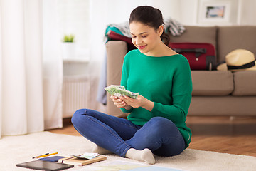 Image showing happy woman with money and travel map at home