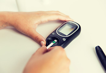 Image showing close up of woman making blood test by glucometer