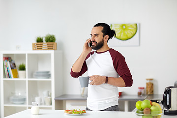 Image showing man calling on smartphone and eating at home