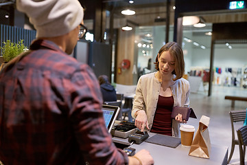 Image showing happy woman paying for purchases at cafe